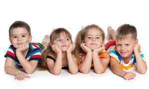 Four preschool children are lying on the floor on the white background